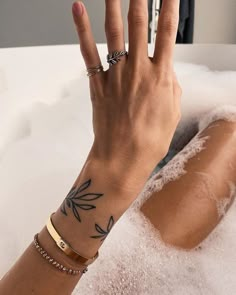 a woman's hand with a tattoo on her left wrist in a bathtub