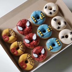 a box filled with donuts covered in frosting and spiderman face designs on them