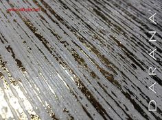 the surface of a wooden table is covered in brown and white paint with gold flecks