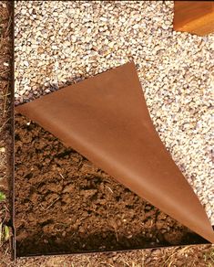 a piece of brown leather sitting on top of dirt next to a wooden bench and grass