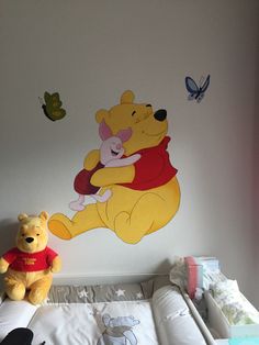 a winnie the pooh wall decal in a child's bedroom with two stuffed animals