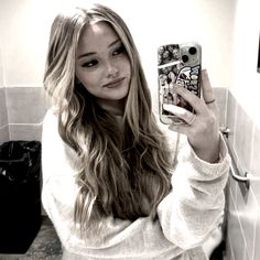 a woman taking a selfie in the bathroom with her cell phone and towel over her shoulder