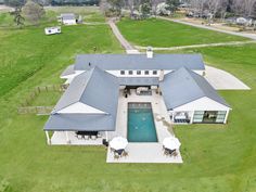 an aerial view of a large house with a pool in the center and covered patio