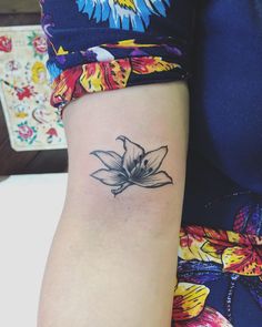 a small black and white flower tattoo on the arm