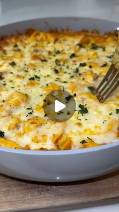 a fork in a casserole dish with cheese and spinach on it, being lifted by a spatula