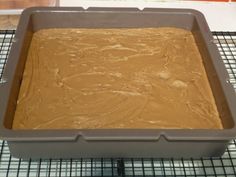 a cake pan filled with chocolate frosting on top of a cooling rack