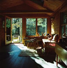 the sun shines through two large windows into a room with wood floors and walls