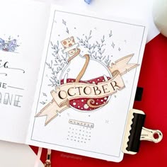 an open notebook with the word october on it next to a pen, scissors and other items