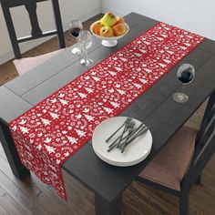 a red table runner with white flowers and berries on it, along with silverware