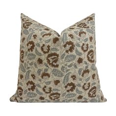 a brown and blue pillow with leaves on it's side, in front of a white background