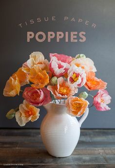 a white vase filled with flowers on top of a wooden table