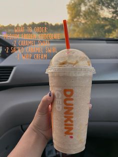 a person holding up a drink in their hand with the words dunkin'written on it