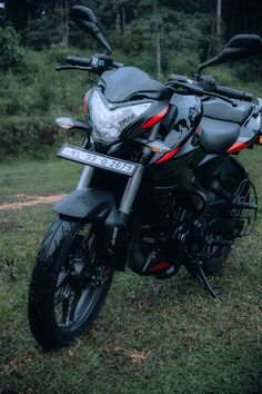 a black motorcycle parked on top of a lush green field next to trees and bushes