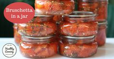 several jars filled with tomatoes sitting on top of a table