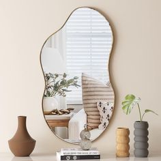 a mirror sitting on top of a white table next to vases and a potted plant