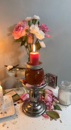 a table topped with a cake covered in frosting and flowers next to a lit candle