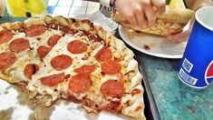 a slice of pepperoni pizza sitting on top of a table next to a drink