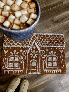 someone is standing on the floor next to a cup of coffee with marshmallows in it