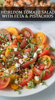 heir tomato salad with feta and pistachios in a white bowl on a table