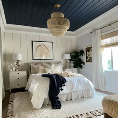 a bedroom with white bedding and blue ceiling