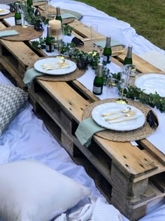 an outdoor table set up with plates and wine bottles