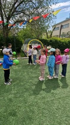 several children are standing in the grass with balloons