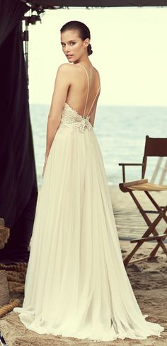 a woman in a wedding dress standing on the beach