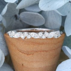 a close up view of a wedding ring on top of a wooden vase with flowers in the background