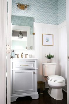 a white toilet sitting in a bathroom next to a sink and a wooden counter top