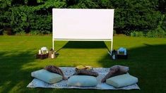 an outdoor movie screen and pillows on the grass