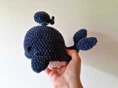 a hand is holding a knitted toy whale