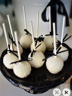 there are some white cake pops on the black plate