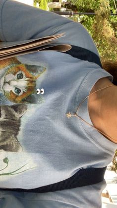 a person wearing a shirt with a cat on it's chest holding a pair of scissors