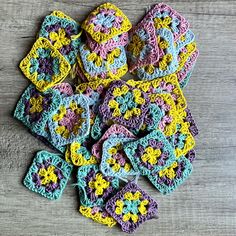 crocheted granny grannys are arranged on a wooden surface, with one square in the middle