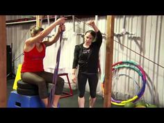 two women doing exercises in a crossfit gym, one is holding the bars above her head