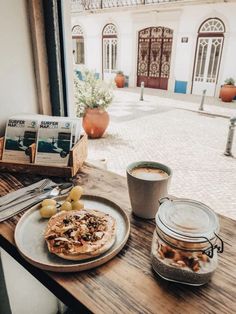 a table topped with a plate of food and a cup of coffee next to a window