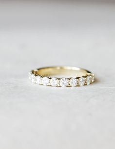 a yellow gold wedding band with five round diamonds on the inside and outside, sitting on a white surface