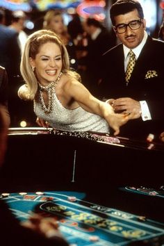 a man and woman are playing roulege in a casino room with other people