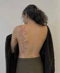 the back of a woman's body with a tattoo on her left arm and shoulder