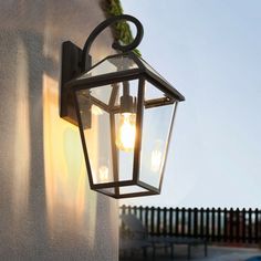 an outdoor light hanging on the side of a building next to a pool and fence