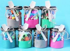 several jars filled with candy and candies on a blue background, one has white tags tied to the top