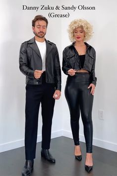 a man and woman standing next to each other in front of a white wall with words on it