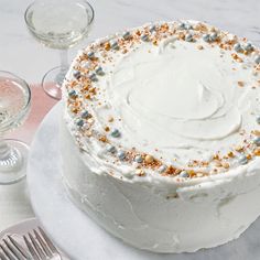 a white cake sitting on top of a table next to wine glasses and silverware