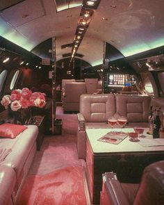 the inside of an airplane with couches, tables and flowers in vases on the table