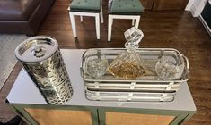 a glass and metal tray on top of a table next to two silver canisters