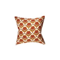 an orange and brown pillow on a white background with a red flower in the center