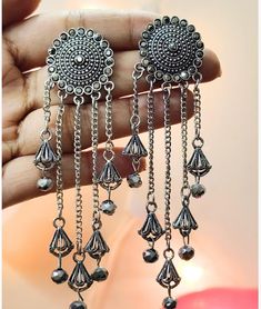 Unleash Timeless Elegance with Silver Mandala Chain Dangle Earrings Adorn yourself with these exquisite silver mandala earrings, crafted with precision and artistic flair. Featuring a circular mandala design with cascading chains and ethnic-inspired bell accents, these earrings are a celebration of intricate craftsmanship. Perfect for festive occasions, elegant evenings, or as a special gift, they embody the spirit of bohemian elegance and cultural richness. Materials Used: High-quality Silver D Silver Metal Chandelier Earrings With Tassels, Silver Dangle Earrings With Tassels, Bohemian Earrings With Latkans For Festive Occasions, Bohemian Drop Jhumkas For Festivals, Bohemian Metal Earrings With Latkans, Bohemian Dangle Earrings For Festive Occasions, Bohemian Dangle Jhumkas, Bohemian Tassel Earrings With Latkans For Festivals, Fusion Style Metal Dangle Jhumkas