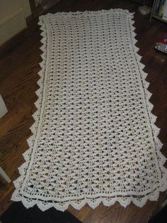 a white crocheted tablecloth on the floor in front of a bookcase