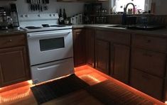 a kitchen with wooden cabinets and white stove top oven in the center, illuminated by red lights