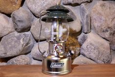 a metal and glass lantern sitting on top of a wooden table next to some rocks